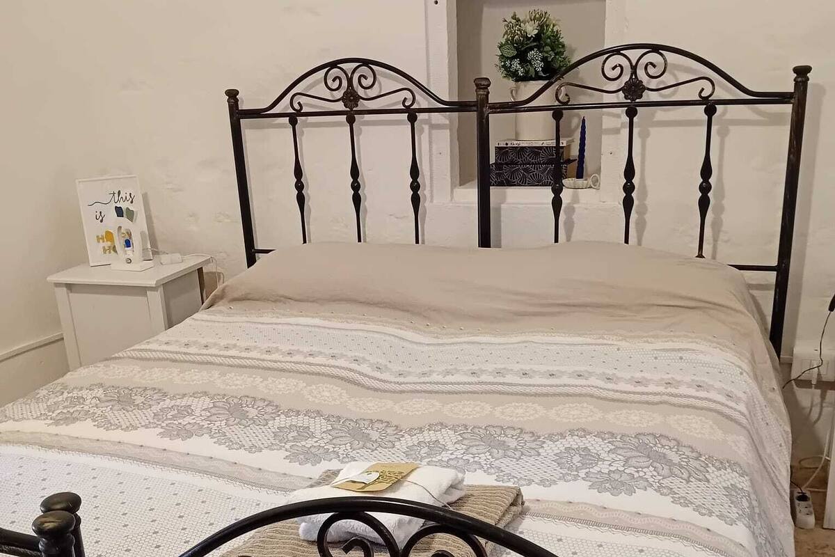 Un lit avec un cadre en métal et une couvre-lit à motifs.