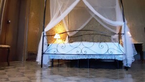 Une chambre avec un lit sous un dais, des décorations élaborées au plafond et un sol à motifs.