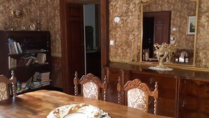 Une salle à manger avec une table en bois, des chaises, une bibliothèque et un miroir au mur.