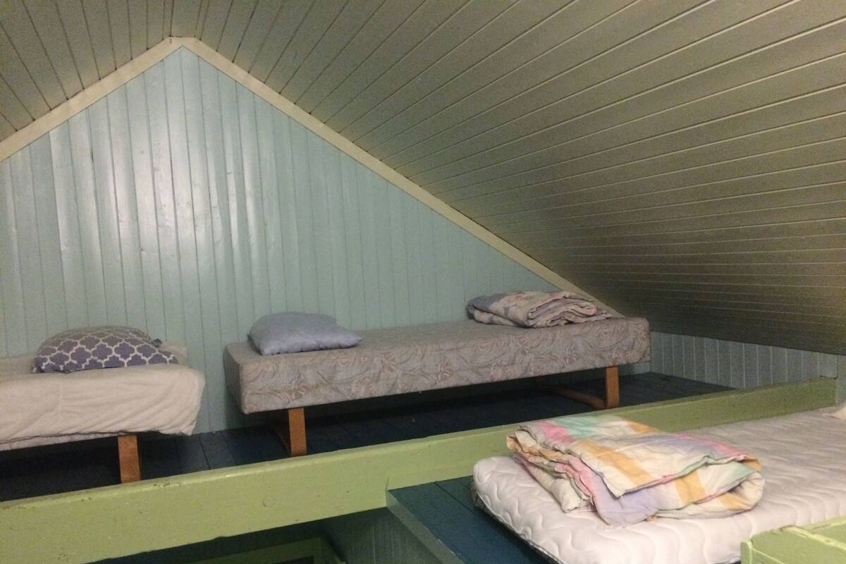 Ein Schlafsaalzimmer mit drei Etagenbetten und einem kleinen Fenster.