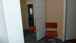 A room with a glass partition, a red chair, and a door. - Cozy apartment 5 (Zeulenroda-Triebes)