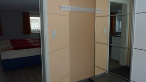 A hotel room with a bed, a mirror, and a wardrobe. - Cozy apartment 5 (Zeulenroda-Triebes)