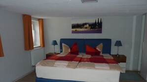 A bedroom with a bed, two bedside tables, a window with curtains, a painting on the wall, and a radiator. - Cozy apartment 5 (Zeulenroda-Triebes)
