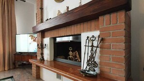 A living room with a brick fireplace, a television, and a decorative mirror.