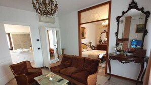 A living room with a sofa, chairs, a coffee table, a chandelier, and a mirror.