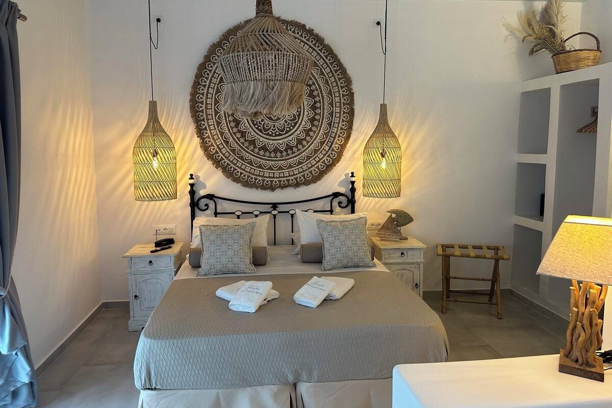 Ein ordentlich eingerichtetes Schlafzimmer mit einem großen Bett, zwei Nachttischen, einer Wanddecke und einer Nachttischlampe.