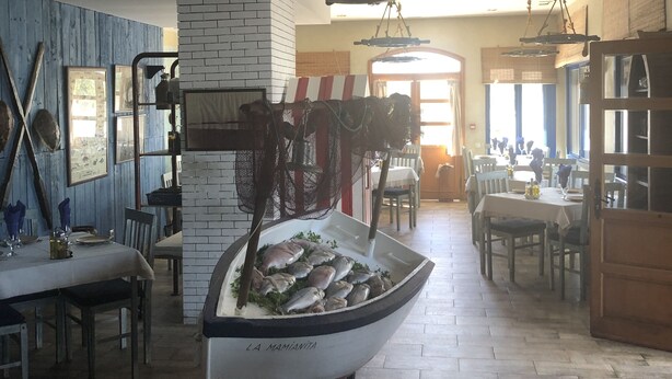 Un restaurante con un carro de servicio con forma de barco lleno de pescado, pisos de madera y una pared de ladrillo.