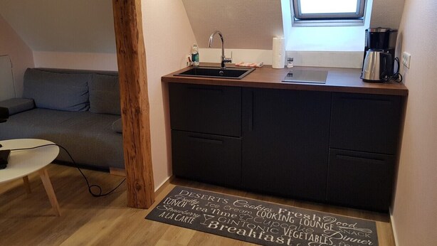 A compact kitchenette with a sink, a coffee maker, and a chalkboard menu listing breakfast items. - Cozy apartment 6 (Zeulenroda-Triebes)