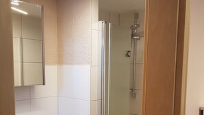 A bathroom with a glass shower enclosure, a white sink, and a mirror. - Cozy apartment 6 (Zeulenroda-Triebes)