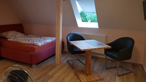 A small, cozy room with a bed, two chairs, a table, and a skylight. - Cozy apartment 6 (Zeulenroda-Triebes)