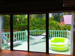 Un balcó amb vista a un jardí exuberant, una cadira espanyola i una piscina inflable.