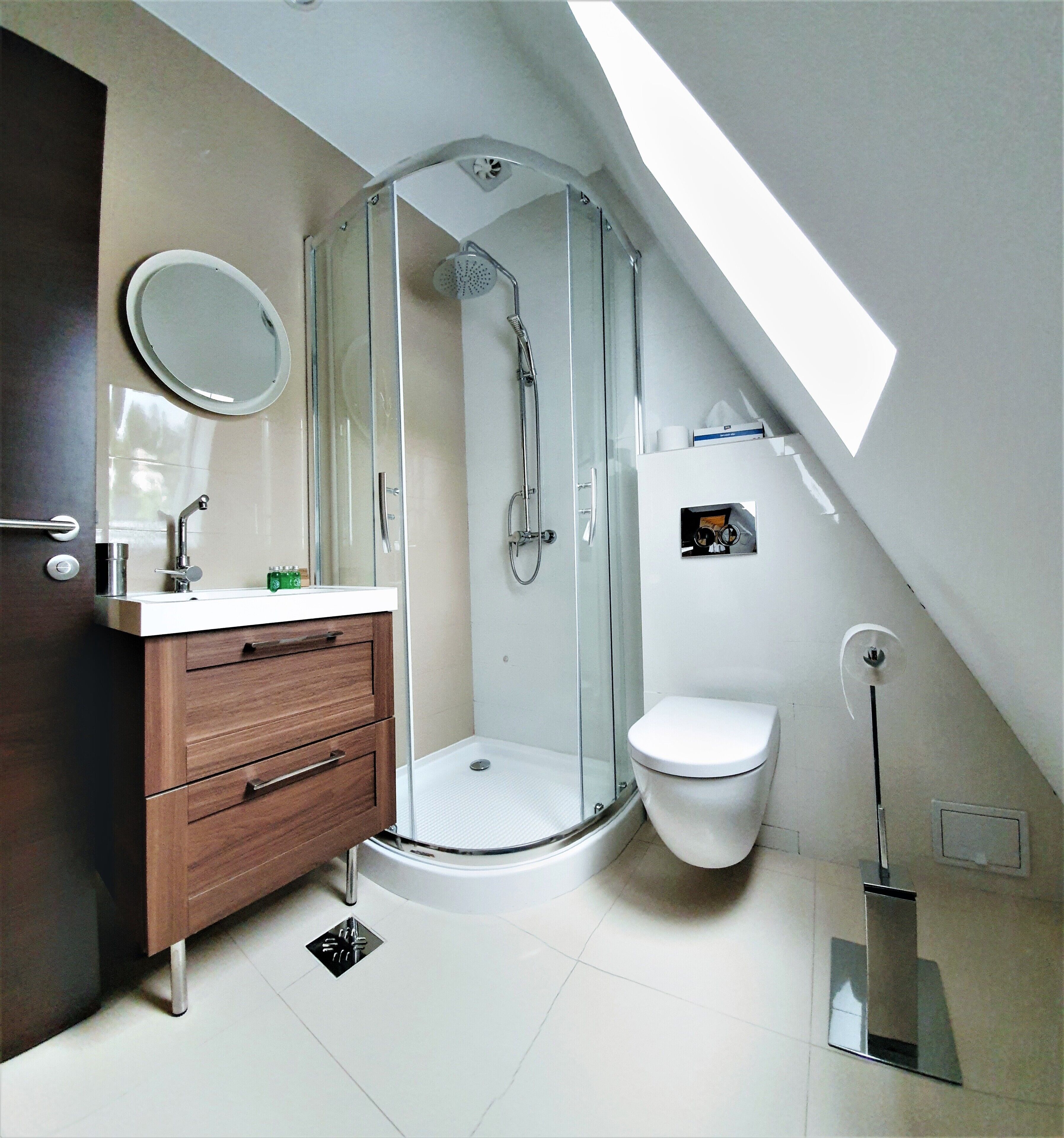 A modern bathroom with a glass-enclosed shower, a toilet, a vanity with drawers, and a mirror.