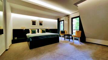 Habitación de hotel moderna con una cama grande, un escritorio y una silla. Hay dos lámparas de pared y una ventana con vistas a zonas verdes.