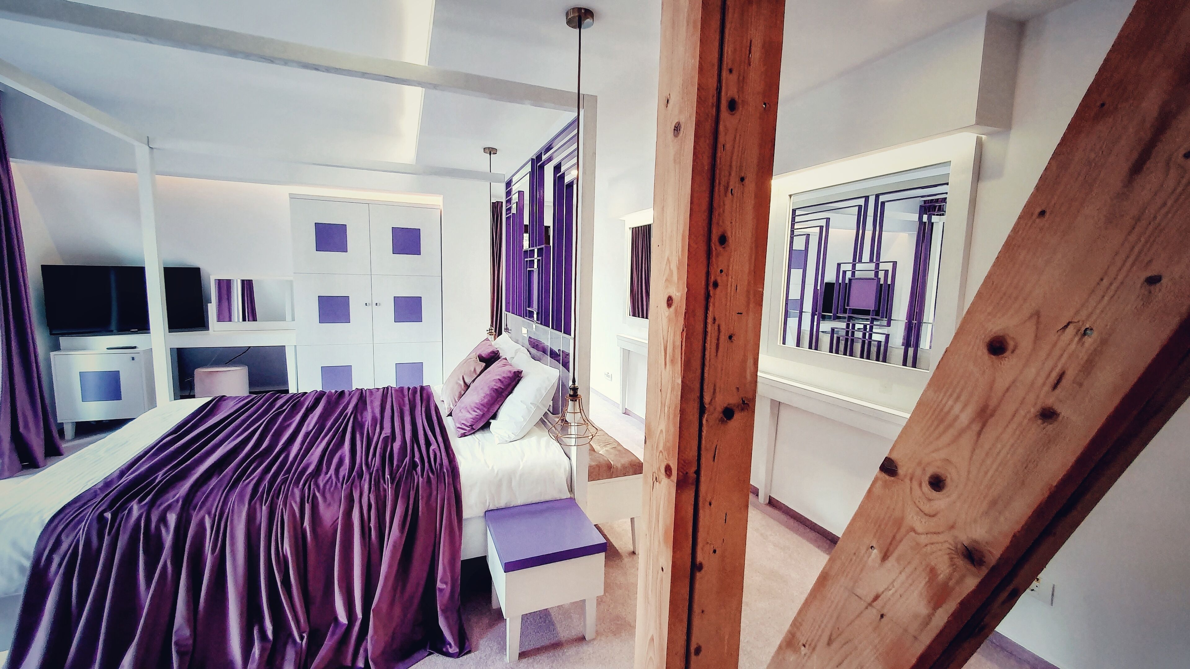 Un dormitorio moderno con cama, mesitas de noche, armario y televisor.