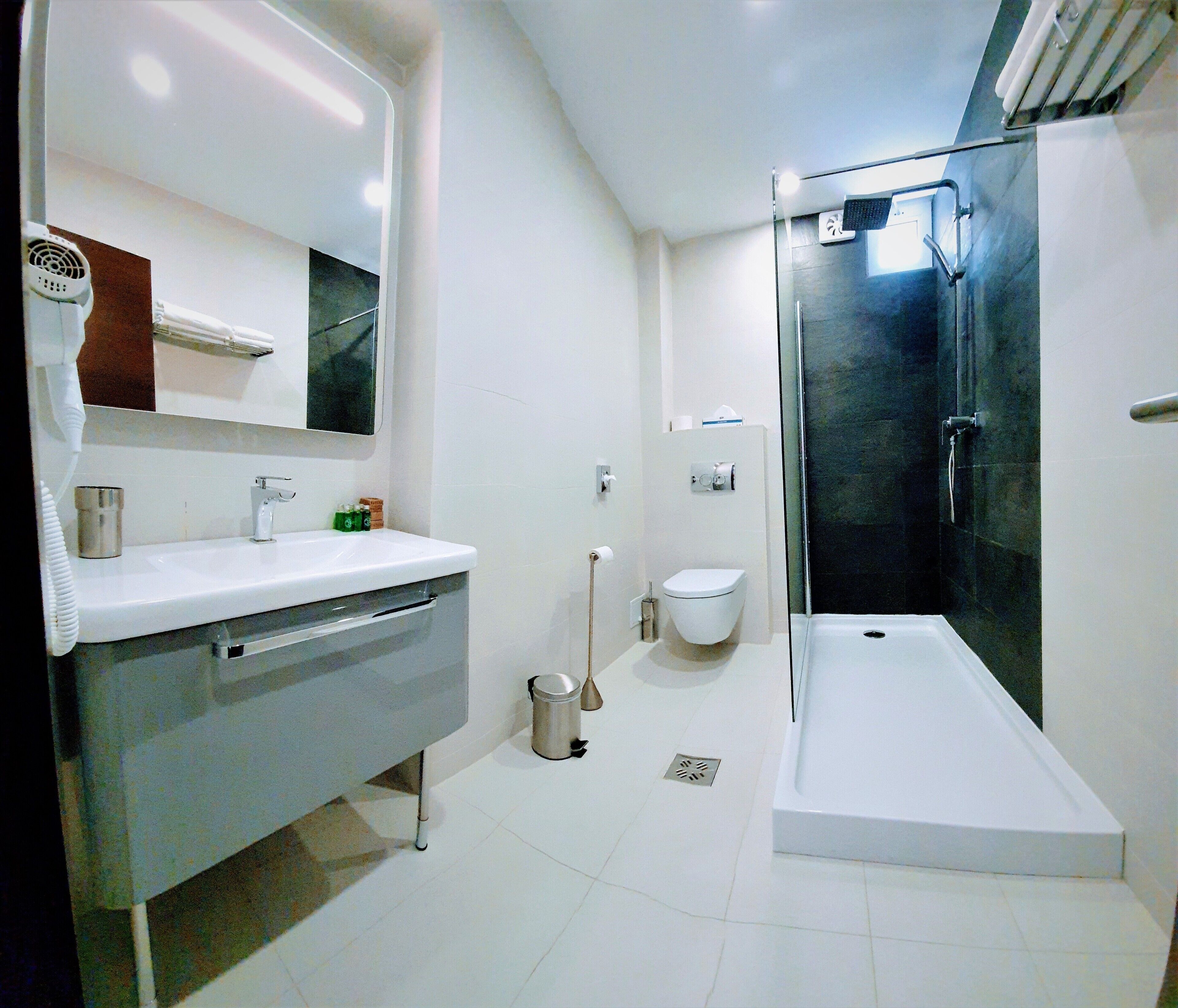 A modern bathroom with a white sink, mirror, and toilet, a glass shower enclosure, and a white bathtub.