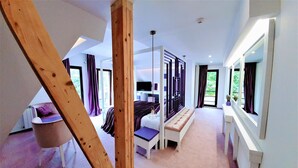 Een moderne slaapkamer met een groot bed, een bankje en een televisie.