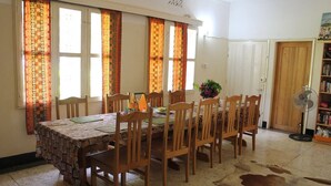 Un coin repas avec une table dressée pour six personnes, entourée de chaises en bois, d’une nappe à motifs et d’un tapis en peau de vache sur le sol.