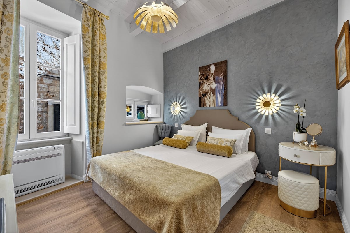 Ein Schlafzimmer mit Bett, Nachttisch und einem Fenster mit Vorhängen.