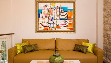A living room with a brown sofa, two green pillows, and a vase on a table.