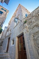 A stone building with a wooden door and a window with a metal frame.