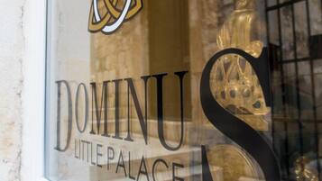 A window with the logo and name "DOMINUS LITTLE PALACE" and a decorative golden emblem.