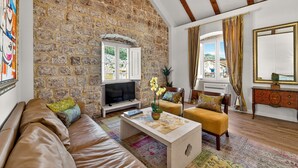 Una sala de estar con una pared de piedra, un sofá, una mesa de centro, un televisor y vistas al exterior.