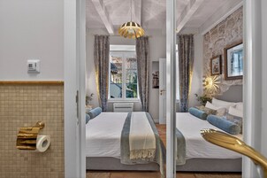 A bedroom with a bed, curtains, a window, and a mirror.