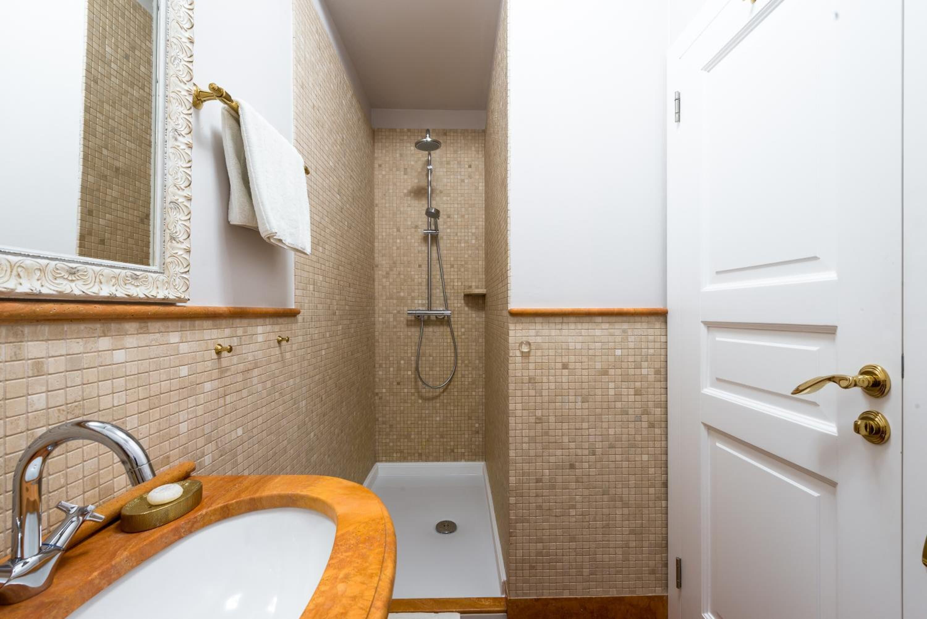 A bathroom with a sink, mirror, and shower.