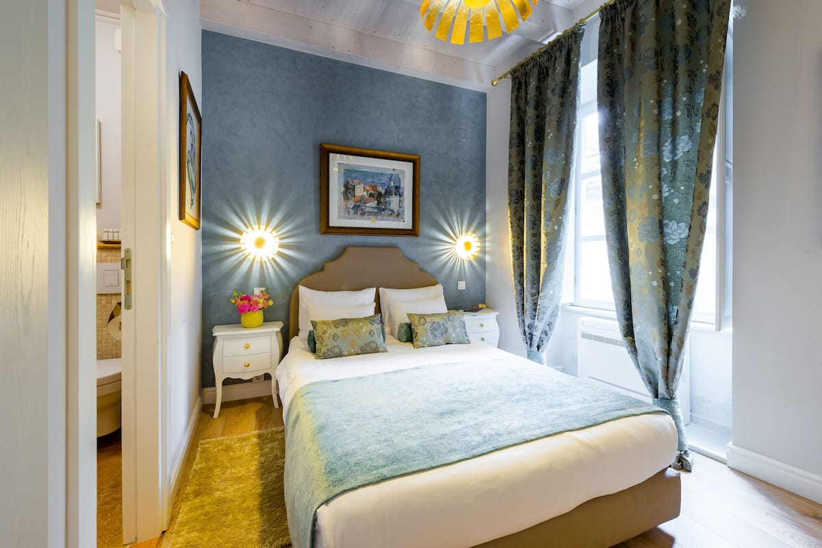 Ein Schlafzimmer mit Bett, Nachttischen, einem Bilderrahmen und Vorhängen.