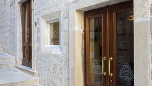 Un edificio de piedra con puerta de madera y una ventana con un letrero.