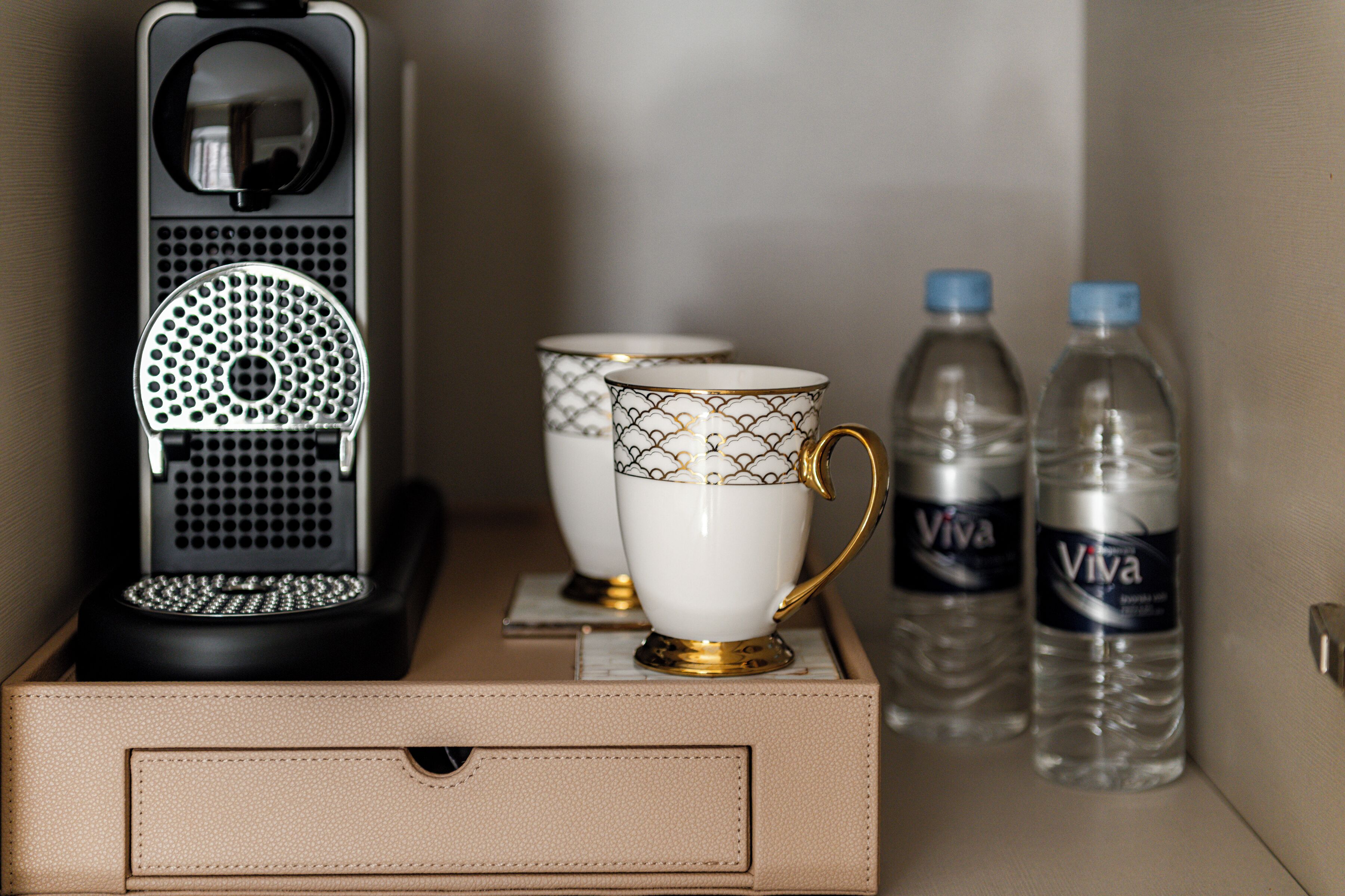 Mini-bar com duas chávenas e duas garrafas de água.