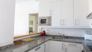A modern kitchen with white cabinets, a granite countertop, a microwave, a kettle, and a toaster. - At sea level, and overlooking the beach.  Apartment with terrace and 8 hrs of sun (Porís de Abona)