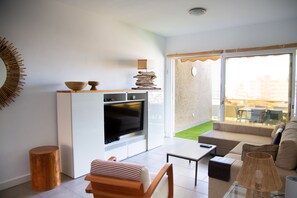 A modern living room with a sofa, a coffee table, a TV, and a dining area with a table and chairs. - At sea level, and overlooking the beach.  Apartment with terrace and 8 hrs of sun (Porís de Abona)