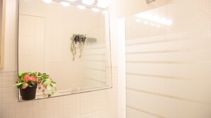 A bathroom with a large mirror, a potted plant, and a shower area. - At sea level, and overlooking the beach.  Apartment with terrace and 8 hrs of sun (Porís de Abona)