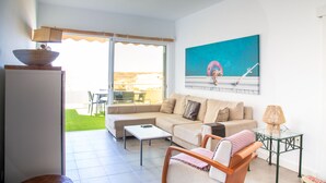 A living room with a sofa, a coffee table, a chair, a lamp, and a painting on the wall. - At sea level, and overlooking the beach.  Apartment with terrace and 8 hrs of sun (Porís de Abona)