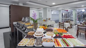 Un bufé con diversas opciones de comida y un comedor con mesas y sillas.
