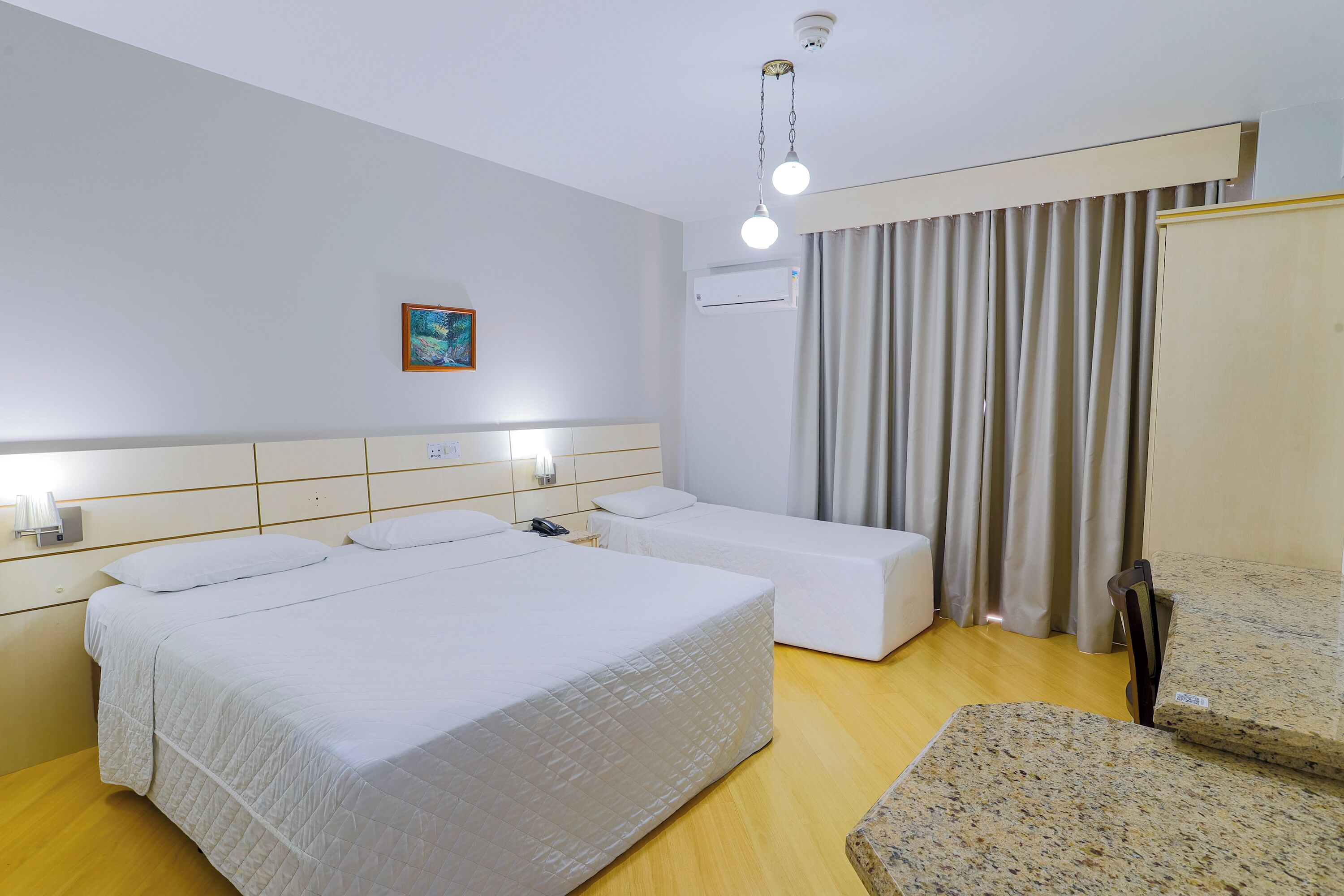 Una habitación de hotel con una cama grande, una cama más pequeña, un escritorio y una silla.