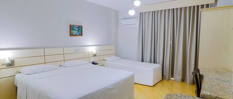 Una habitación de hotel con una cama grande, una cama más pequeña, un escritorio y una silla.