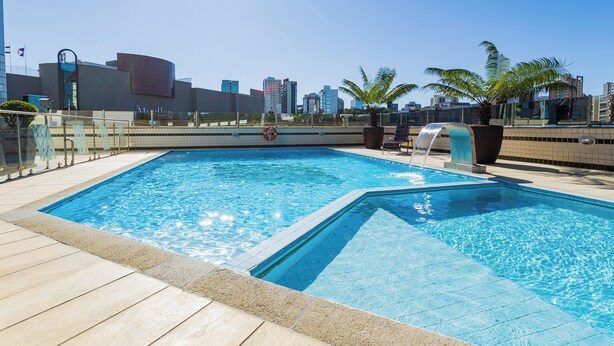 Una piscina en la azotea con el horizonte de la ciudad al fondo.
