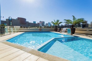 Una piscina en la azotea con el horizonte de la ciudad al fondo.