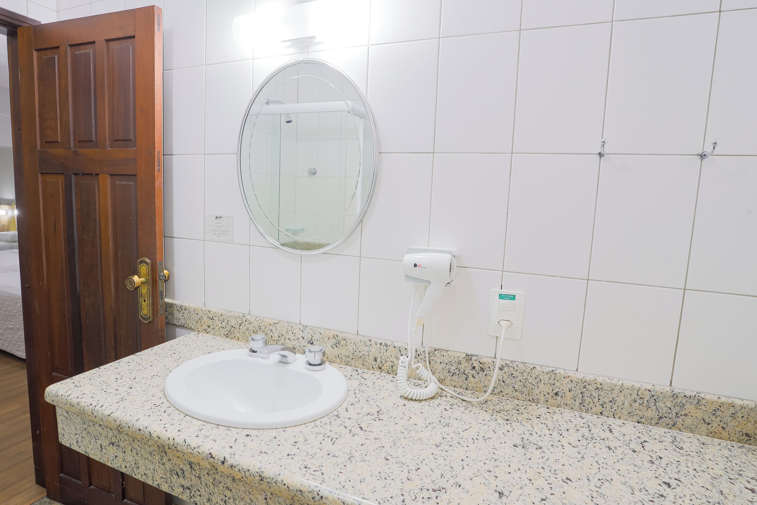 Un baño con encimera de granito, un lavabo blanco, un espejo y un secador de pelo.