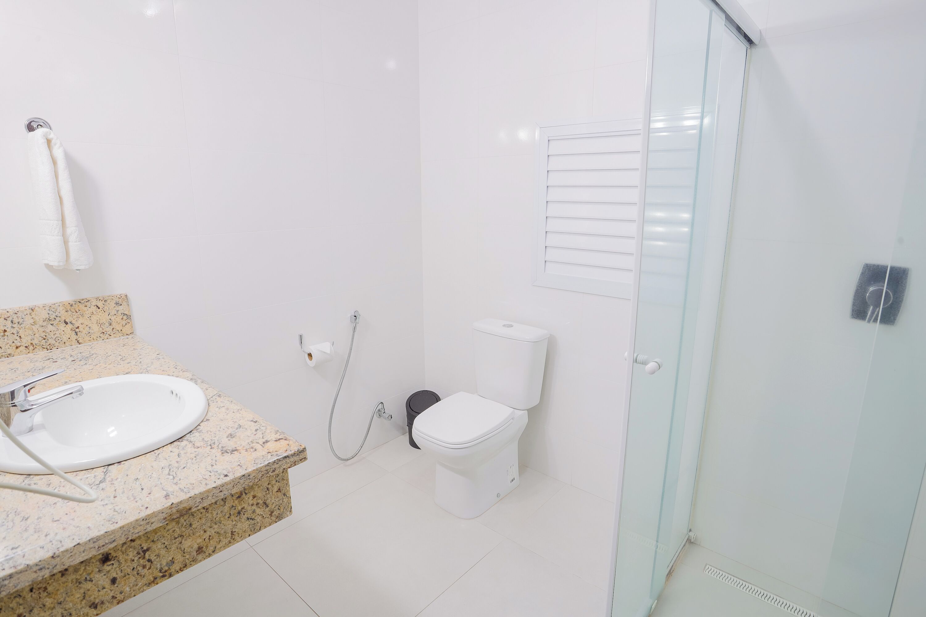 Un baño moderno con lavamanos de granito, inodoro y cabina de ducha con mampara de vidrio.