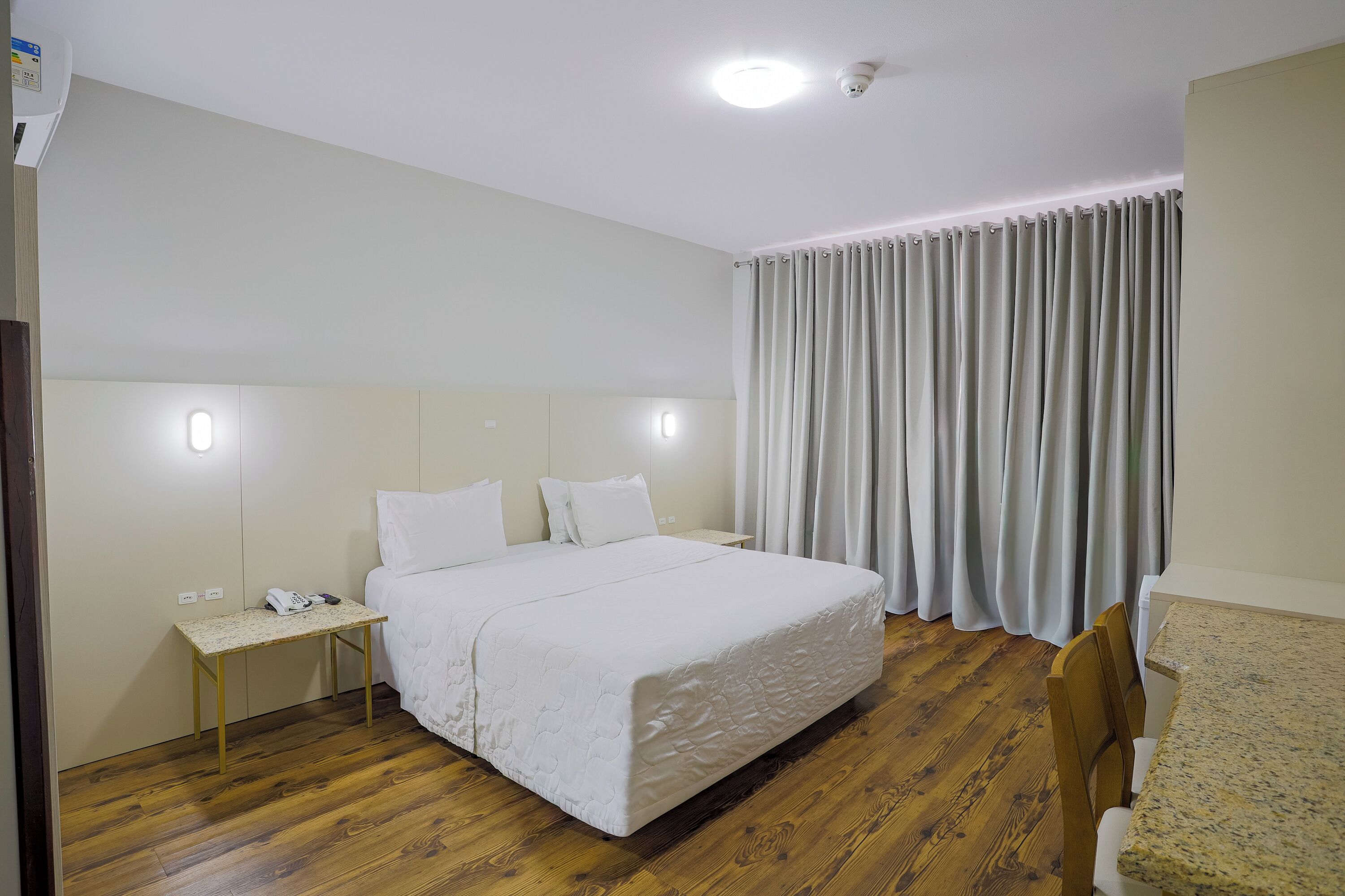 Una habitación de hotel con una cama, una mesita de noche y un escritorio con una silla.