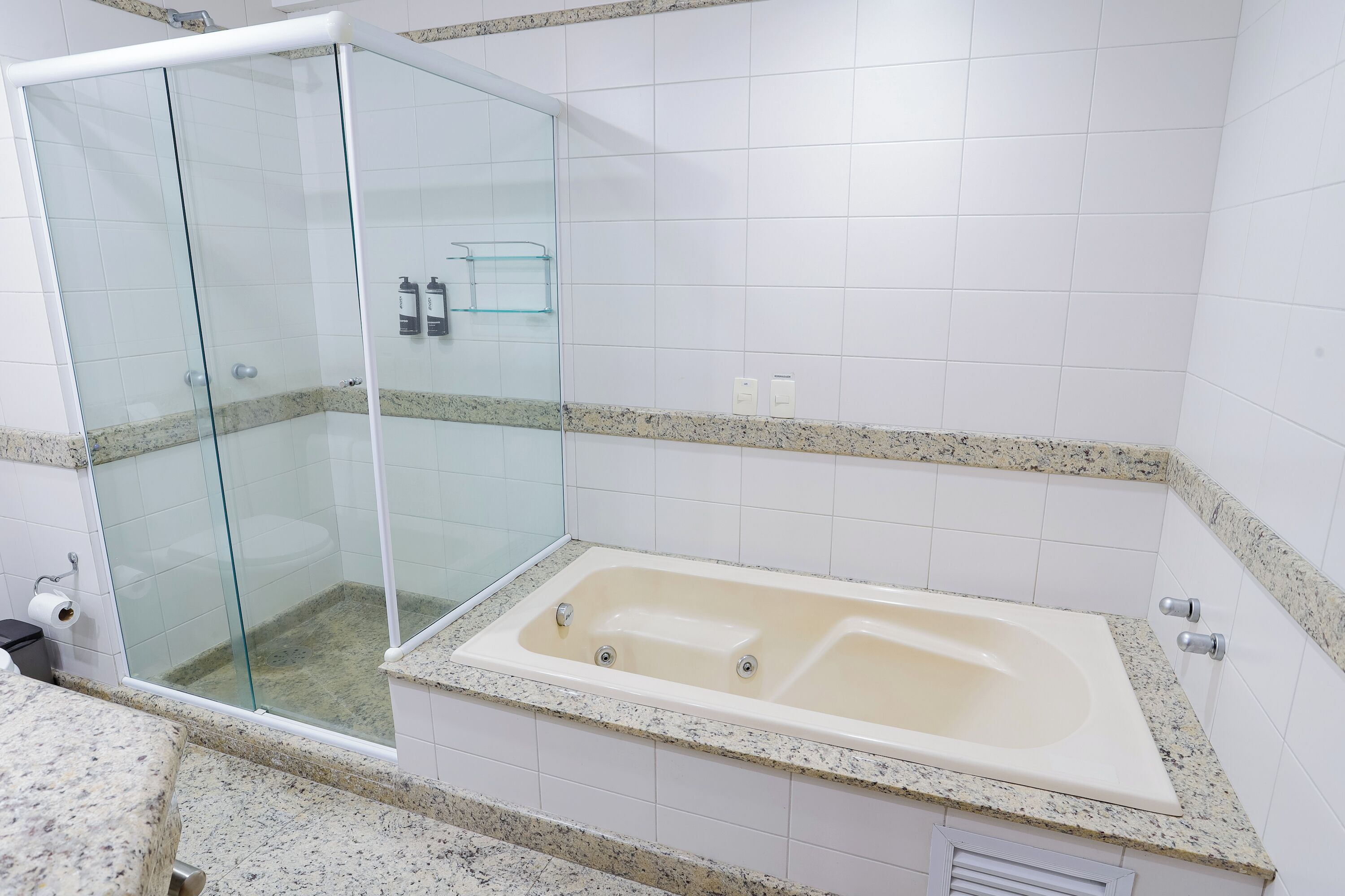 A modern bathroom with a glass-enclosed shower, a freestanding bathtub, and a granite countertop.