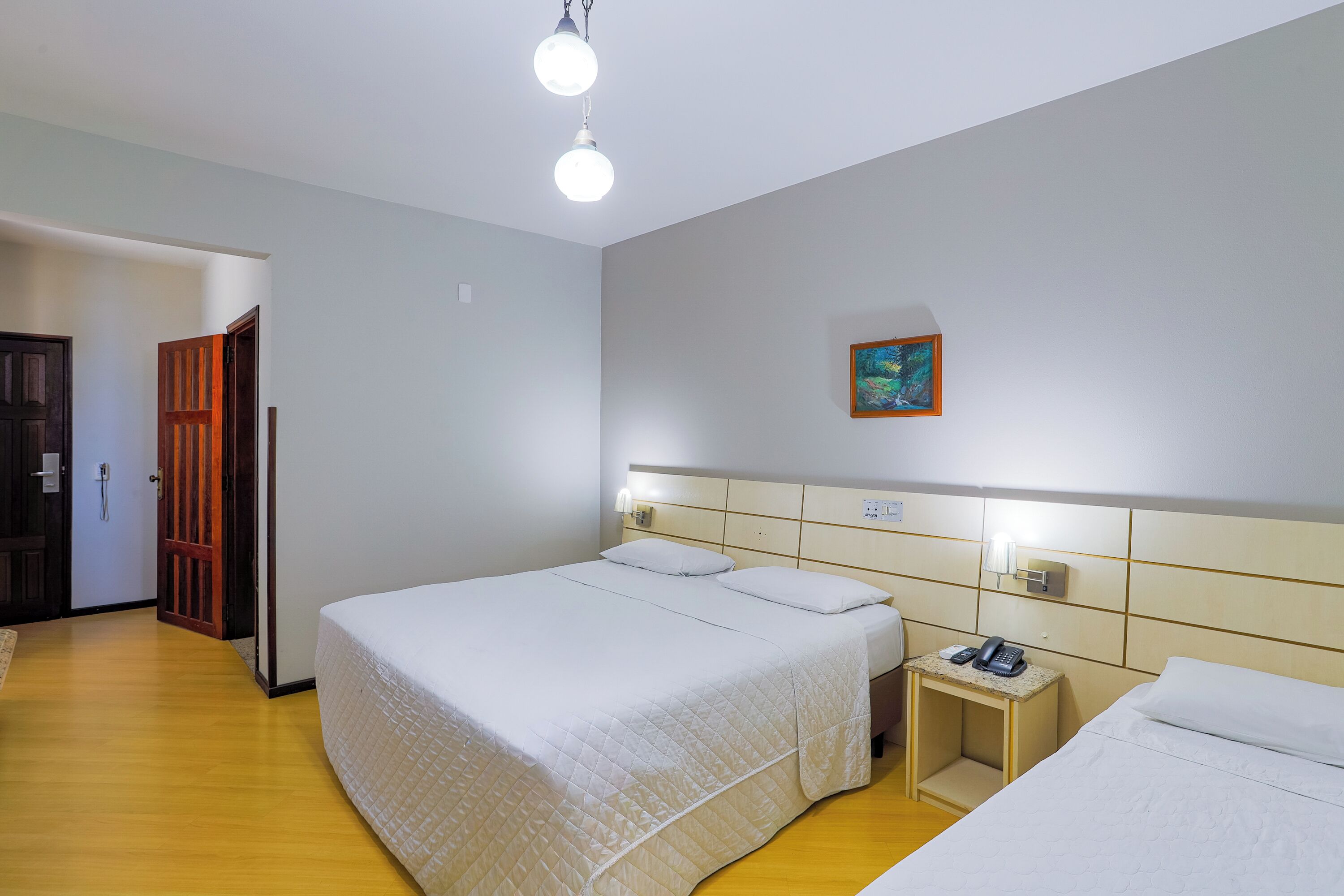 Ein Hotelzimmer mit einem großen Bett, einem Nachttisch mit Telefon und einem Bild an der Wand.