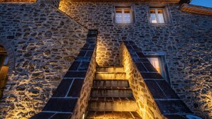 A stone building with a staircase leading to a wooden door. - Podere Fontanino (Arezzo)