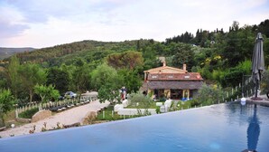 A swimming pool with a view of a house and surrounding greenery. - Podere Fontanino (Arezzo)