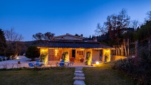 A stone house with a thatched roof, a paved driveway, and outdoor seating. - Podere Fontanino (Arezzo)