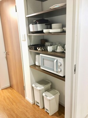 Une cuisine équipée d’un four à micro-ondes, d’un évier et d’une poubelle.