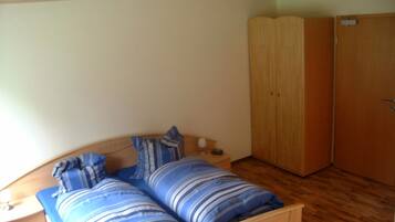 Ein Schlafzimmer mit Bett, Nachttisch, Lampe und Kleiderschrank.